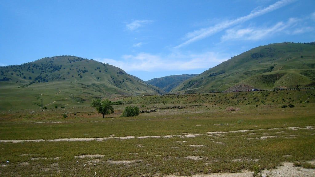 Green California hills and an open valley beneath a clear blue sky